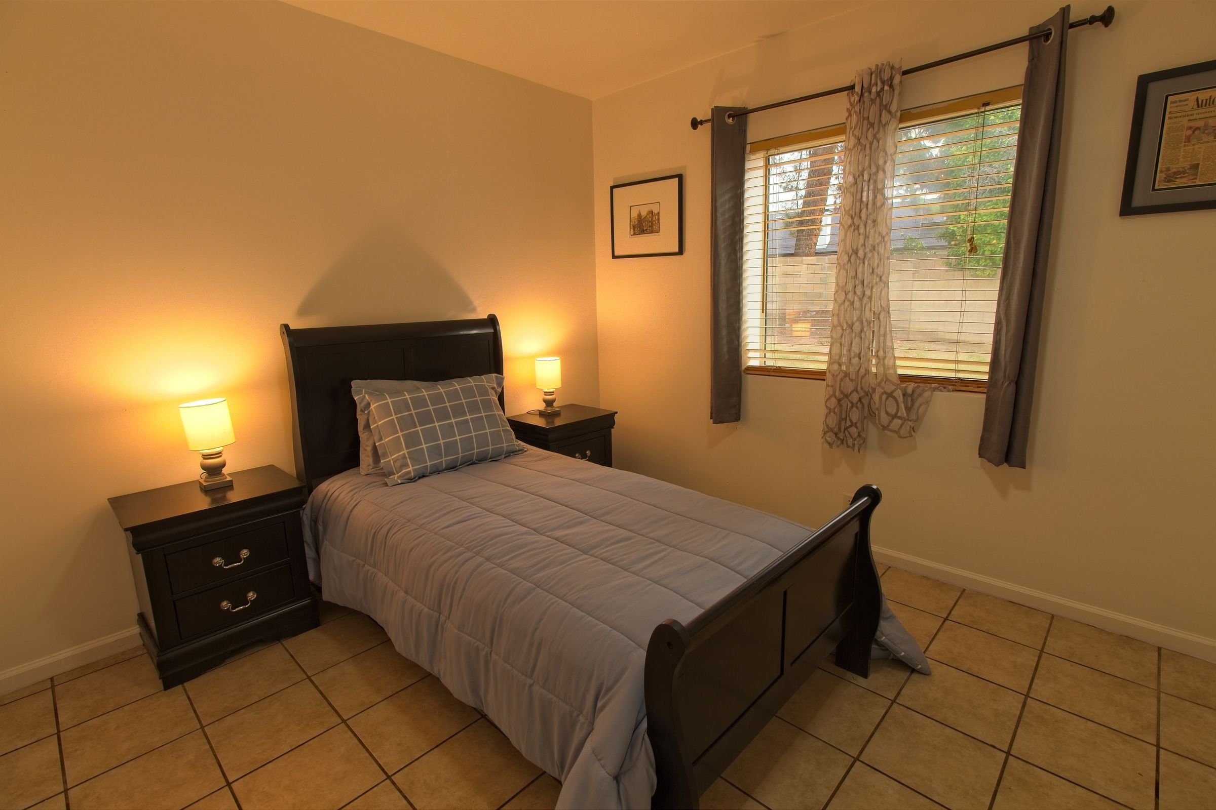 A private bedroom with a dark wood bed, a lamp on the nightstand and a window