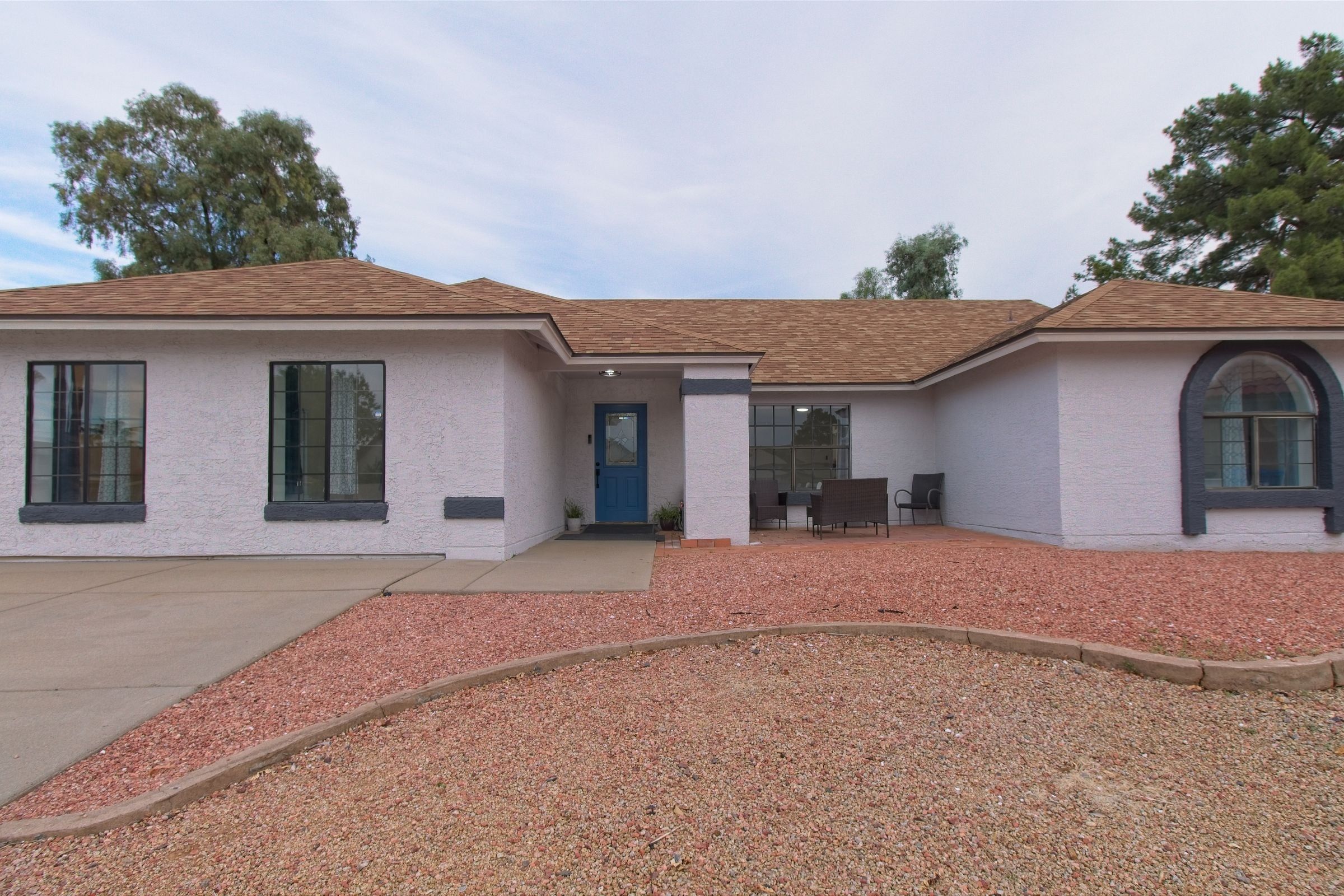 The front of Elite Place for Care: a single-story white house with a blue front door and a covered patio