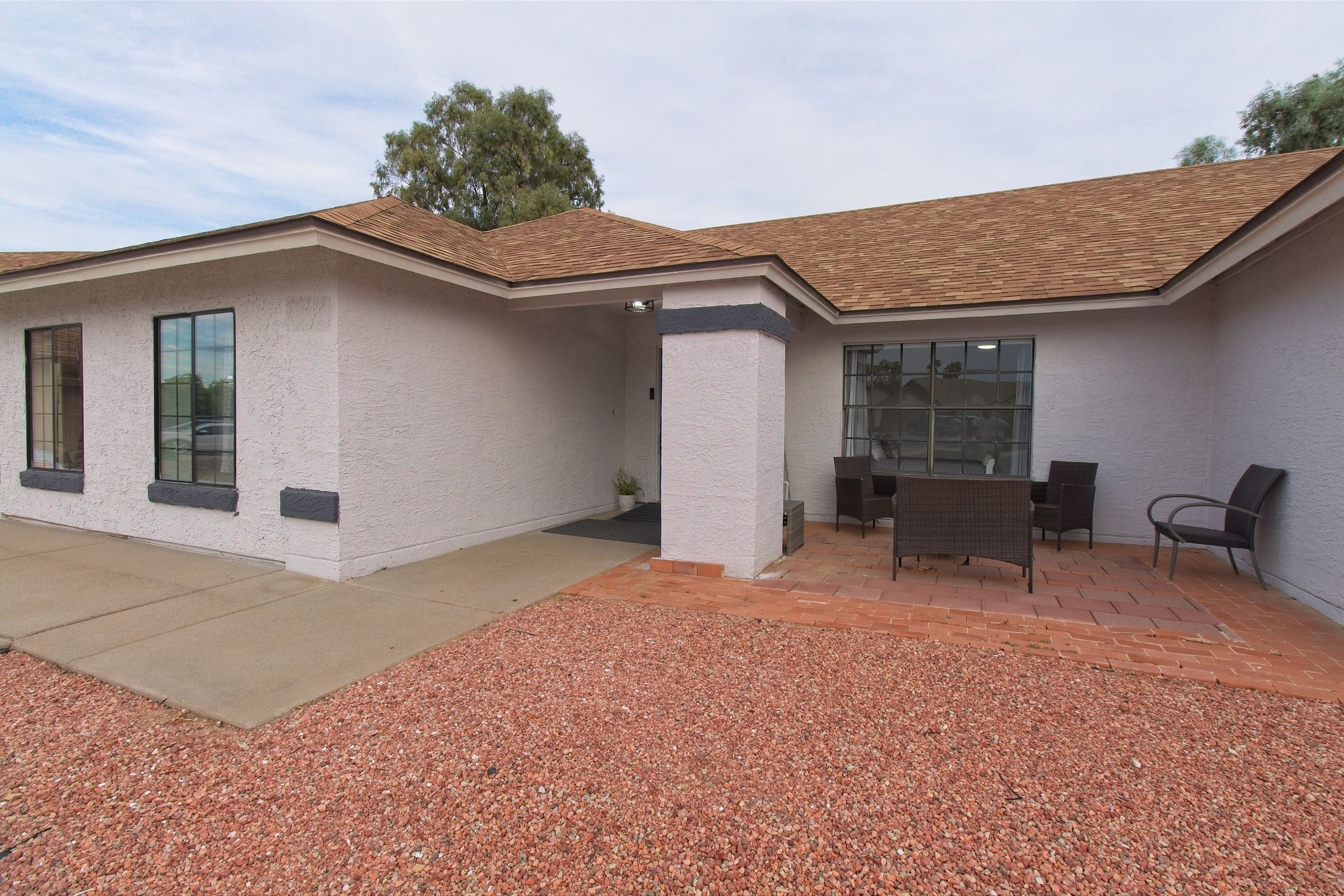 The covered front patio, with outdoor chairs and a small table beside the front door