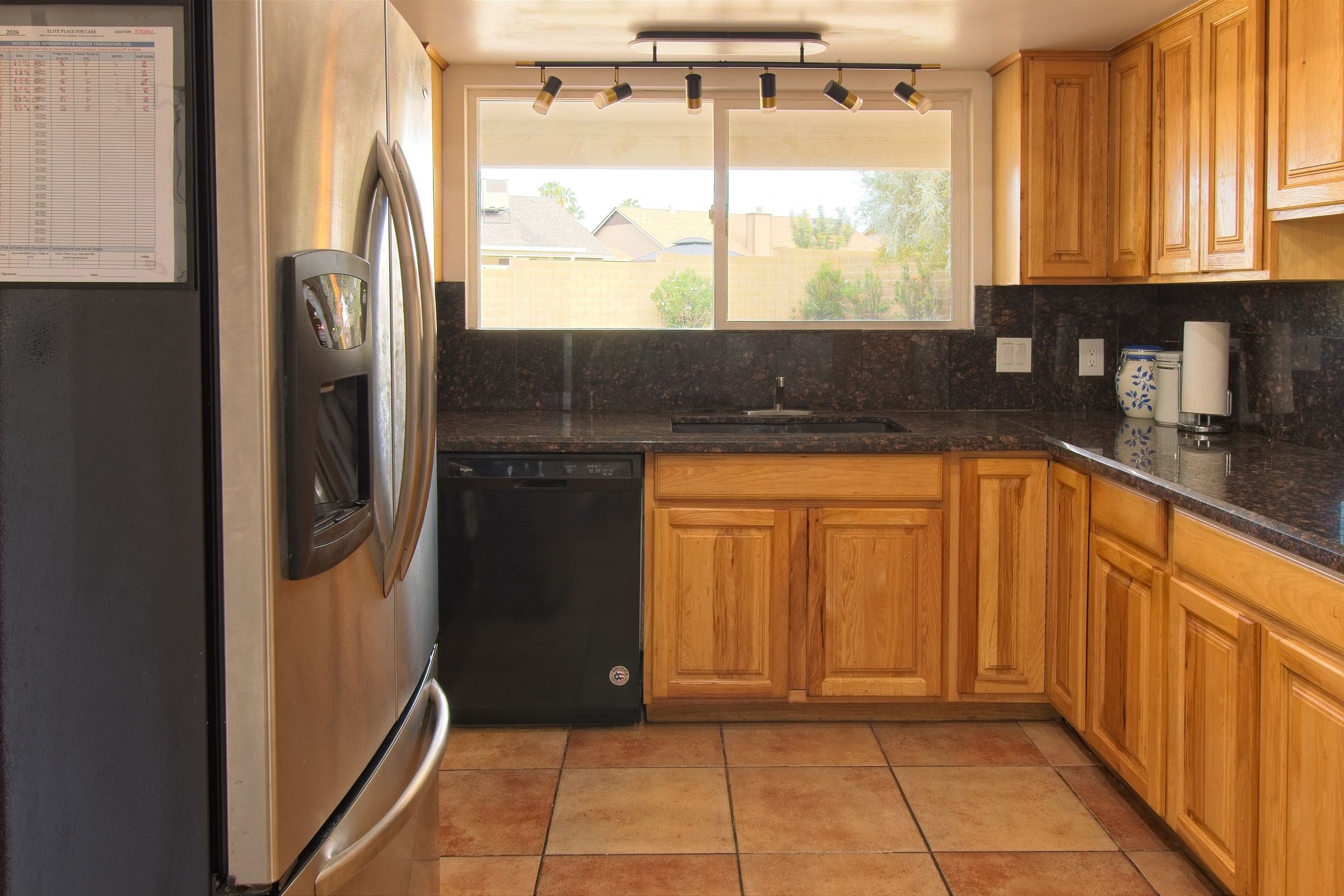 The kitchen, with oak cabinets, black granite counters and a stainless steel refrigerator